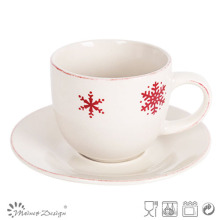 Taza de té y platillo rojo de la nieve de la Navidad